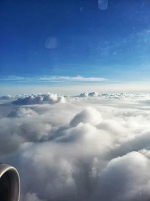 airplane window view above fluffy white clouds