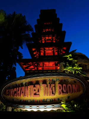 illuminated tiki room sign at night with pagoda