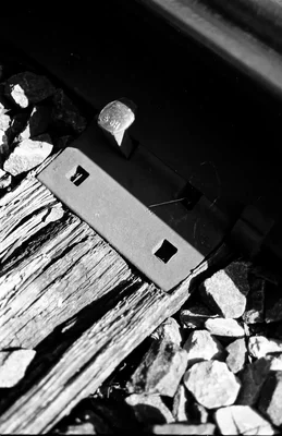 metal rail fastener on weathered wooden railroad tie