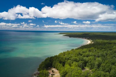turquoise water meets forested coastline under clouds