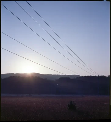 sunset over hills with power lines silhouetted