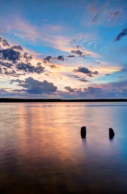 calm lake at sunset with wooden posts