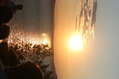 sunset over water with silhouetted figures watching