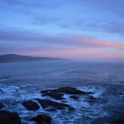 rocky coastline at twilight with pink clouds