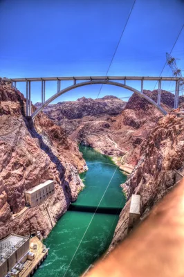 concrete arch bridge spanning desert canyon with river