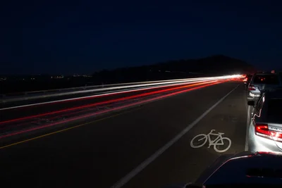 nighttime highway with light trails and bike lane