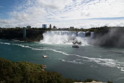 waterfall with tourist boat and city skyline