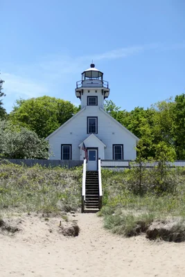 white lighthouse on sandy beach with stairs