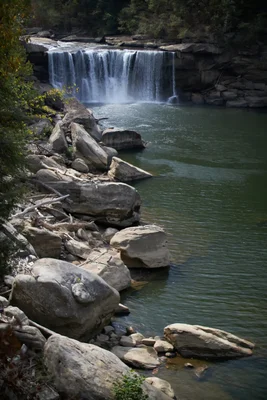 waterfall flowing over rocky ledge into green pool