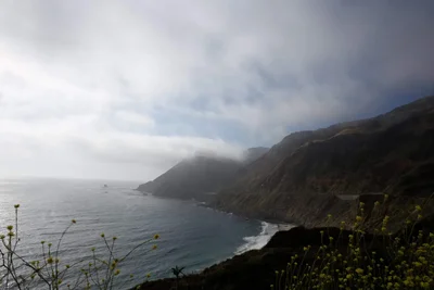 coastal cliffs meeting ocean under cloudy sky