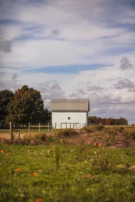 white barn beside pumpkin patch autumn countryside